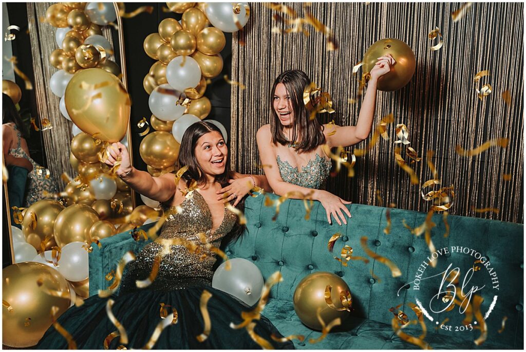 image by bokeh love photography, best friends celebrating new years eve on a green couch, dressed in elegant prom dresses throwing balloons and confetti, NYE Mini Session in South Jersey