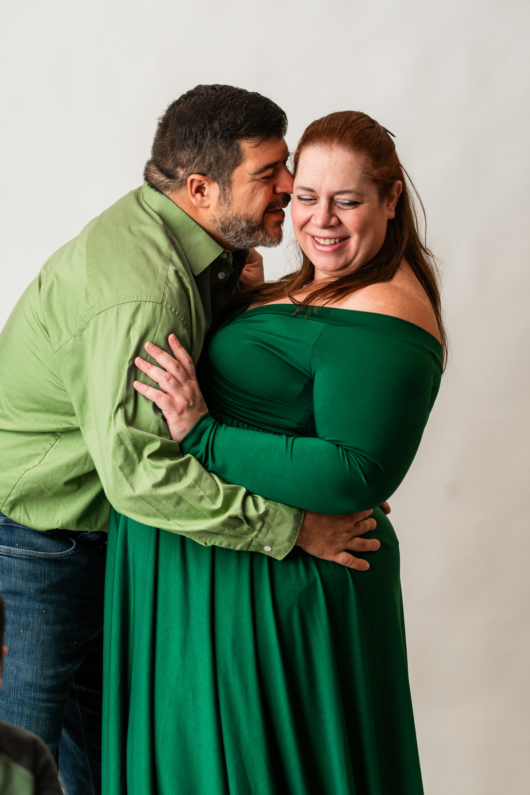 Family maternity portrait with mother, and father together in a studio maternity session in South Jersey, all smiling and interacting naturally