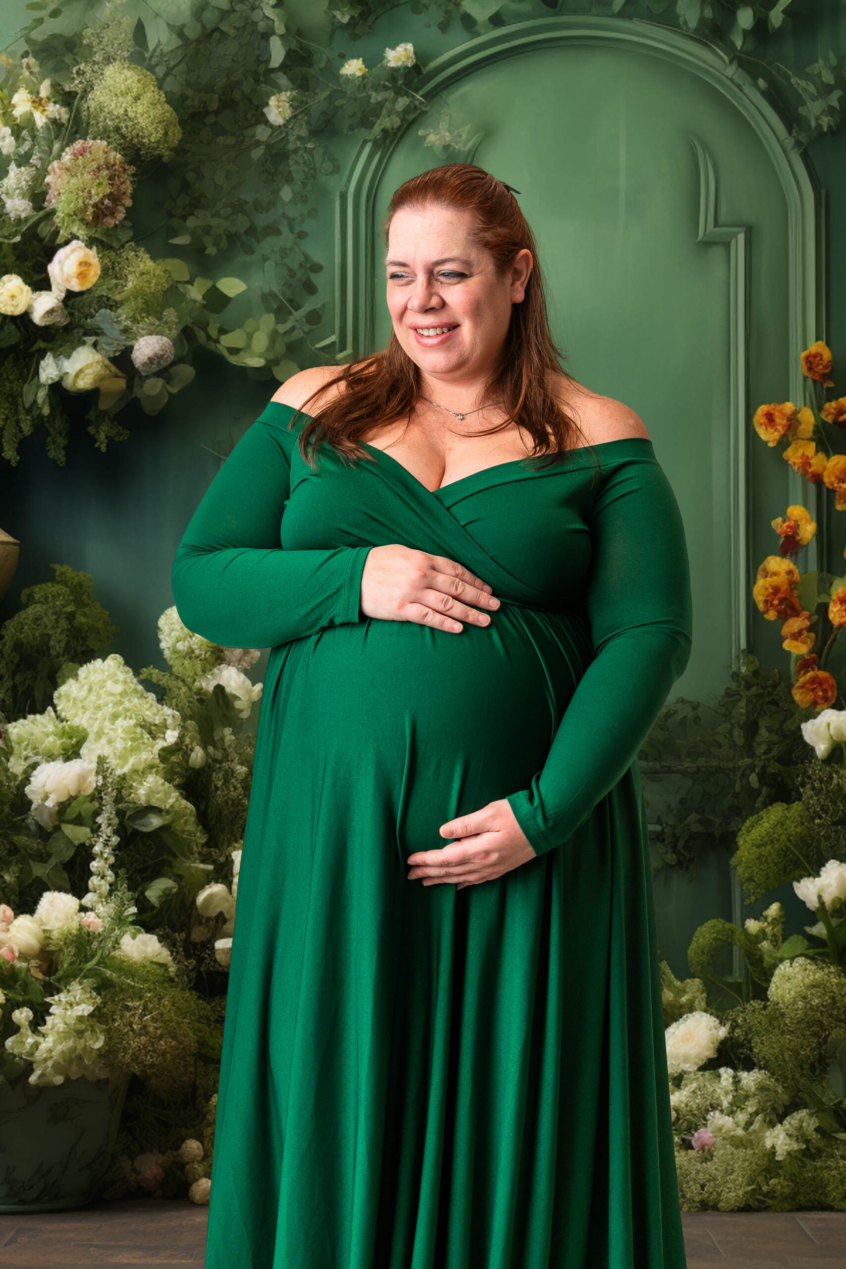 Expecting mother standing under a digital floral arch backdrop with greenery and flowers, captured during a studio maternity session in South Jersey.