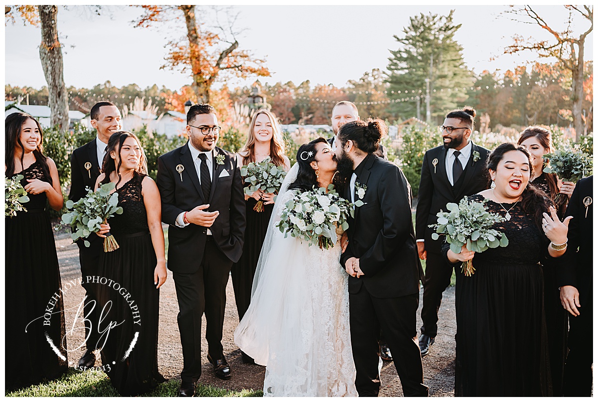 Wedding party at renault winery. Photo by Bokeh Love Photography. October Wedding. Black Bridesmaids Dresses. Bride and Groom kissing. Walking photo Wedding Party.