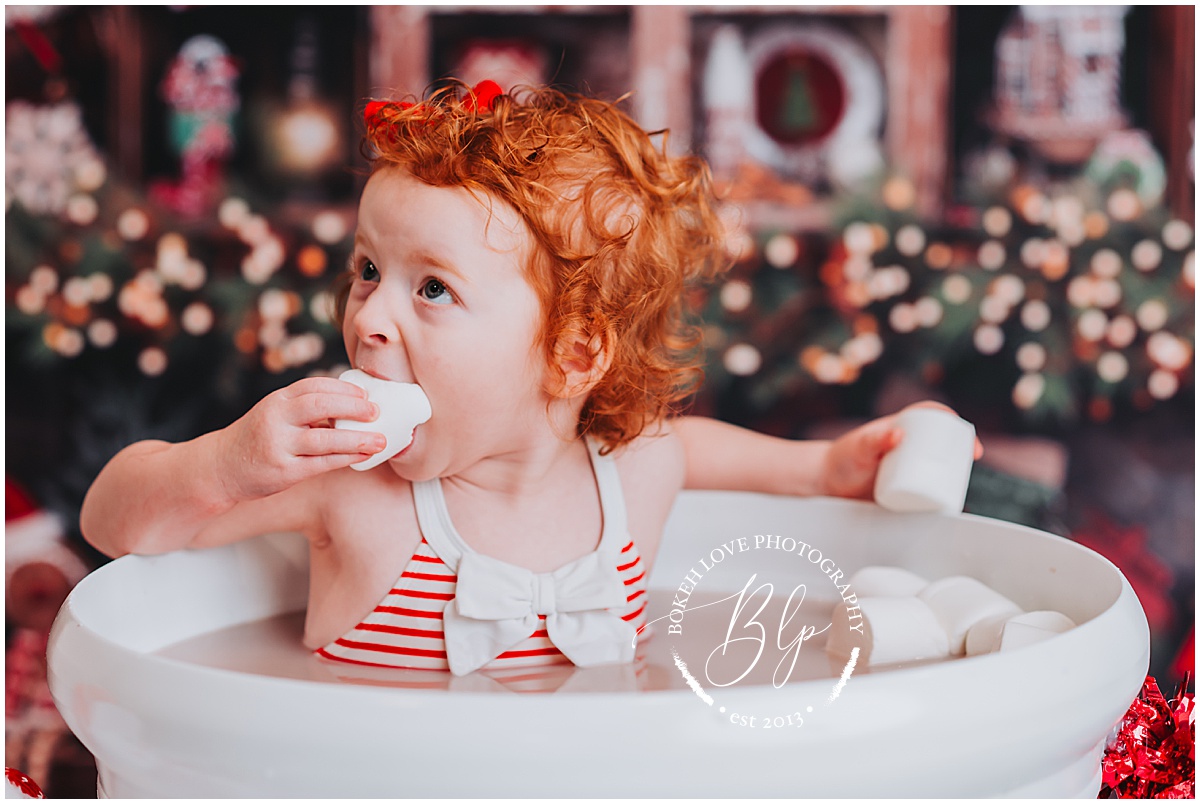 little girl in hot cocoa cup eating giant marshmallow