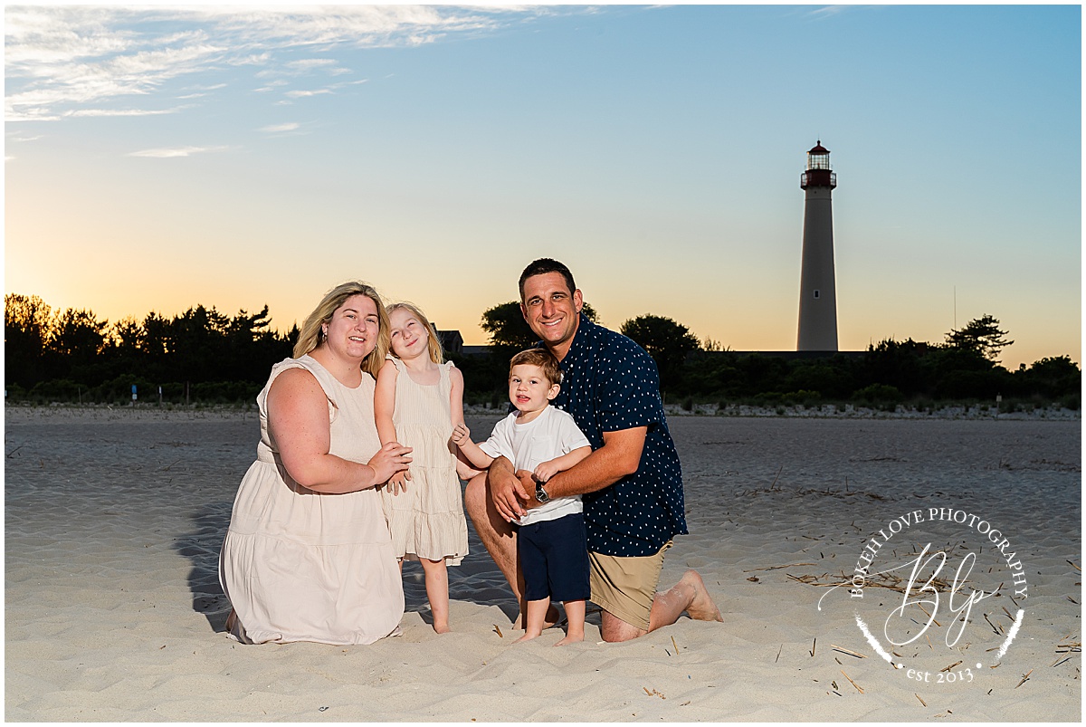 Bokeh Love Photography, Family of 4 at the cape may lighthouse, using off camera lighting to create a dramatic image with a beautiful sunset, both family and sunset are evenly exposed, Cape May Lighthouse Family Portraits