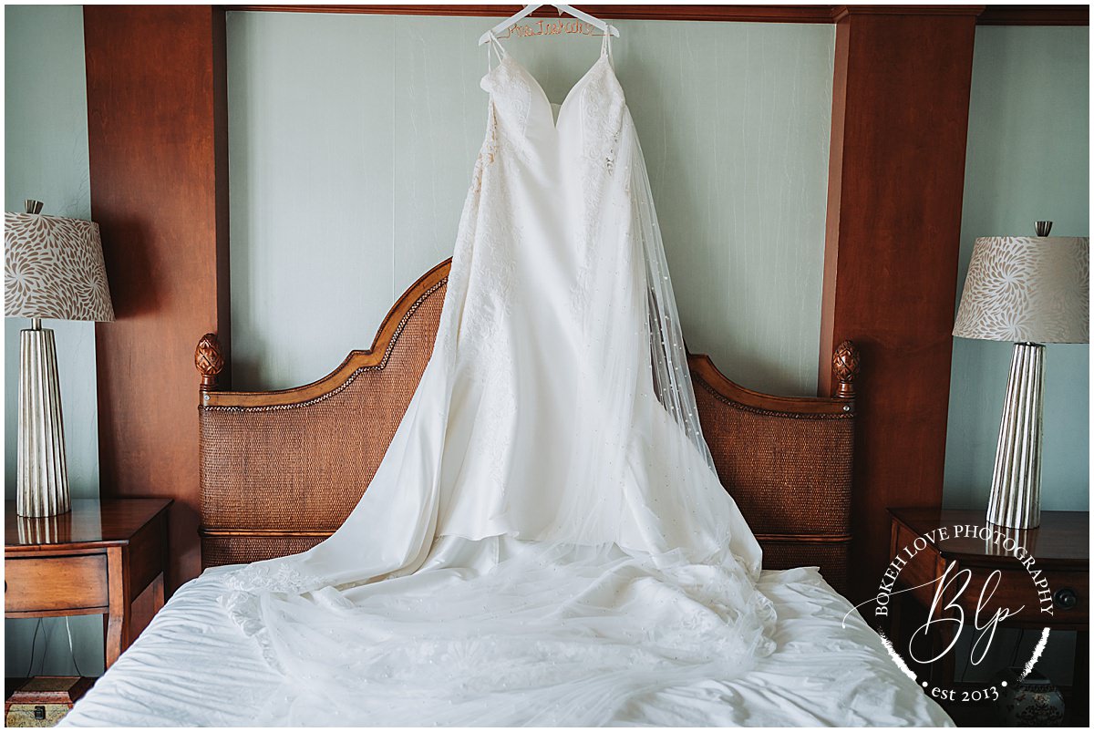Photography by Bokeh Love Photography, Brides wedding dress hanging on a bed at the Flanders Hotel